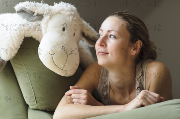 Young woman lying on the couch with a soft toy