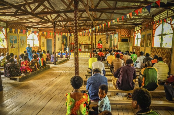 Palembe, Papua New Guinea, July 2015: Photo of native people sitting on wooden benches during mass