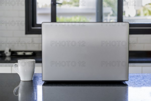 Laptop and cup of coffee on the kitchen island. Home office concept