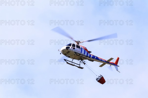 Helicopter with a water bucket during a forest fire, Tyrol, Austria, Europe