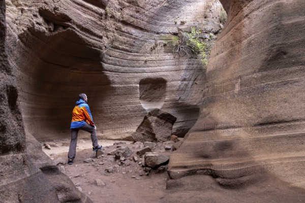 Tourist in sportswear visiting Slot Canyon Toba de Colores, Barranco de las Vacas, Agüimes, Las