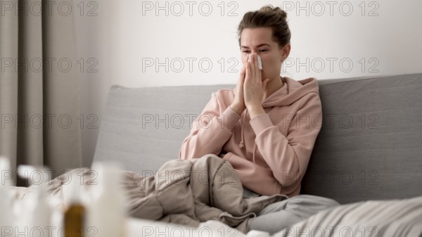 Woman indoors blowing her nose