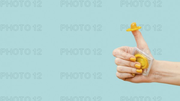 Woman holding yellow condom her finger