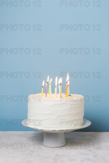 Front view lit candles birthday cake. High resolution photo