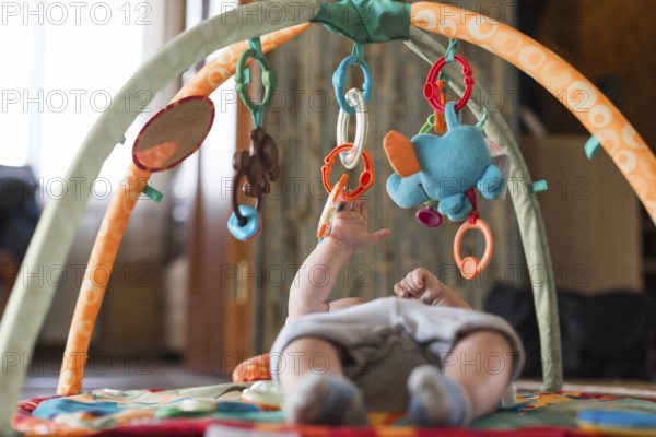 baby lying developing rug with mobile educational toys