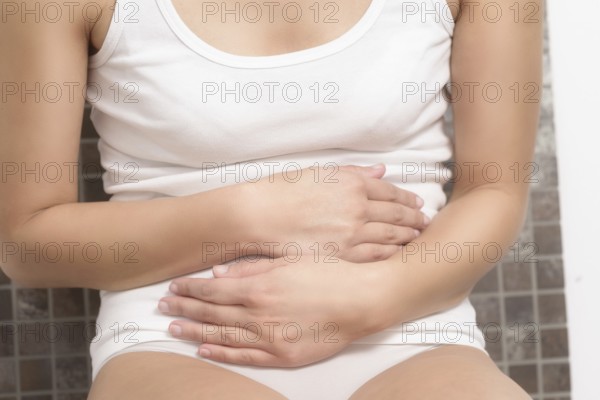Woman with her monthly menstrual pains clutching her stomach with her hands as she becomes stressed