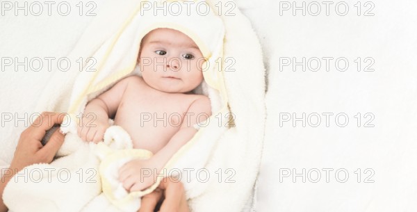 Adorable 6 months old Baby girl infant on a bed on her belly with head up looking into camera with