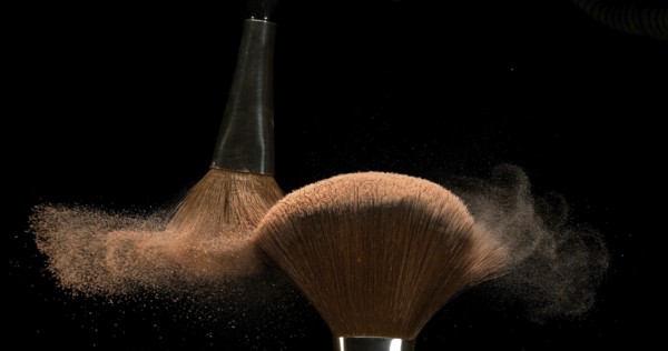 Make-up Brush spreading blush powder on black background