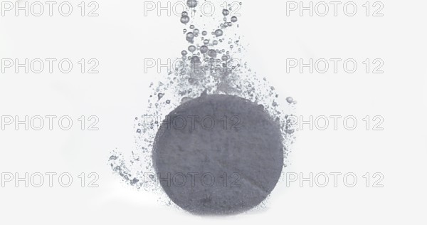 Tablets Falling and Dissolving into a Glass of Water against White Background