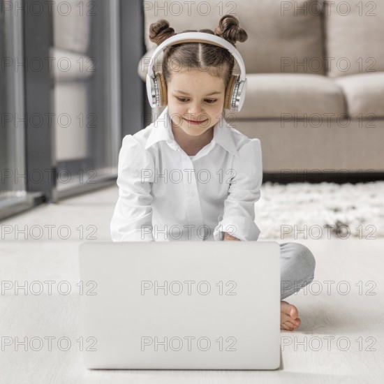 Little girl listening her teacher through headphones home