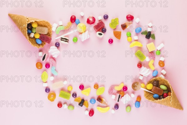 Colorful sweet candies with two ice cream waffle cone pink surface