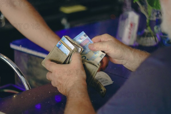 Parma, Italy July 24th 2024 A customer pays the barman at a cafe with a ten euro banknote.
