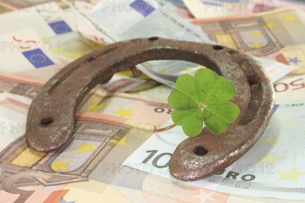 Rusty horseshoe with lucky clover and lots of euro notes