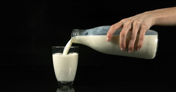 Milk being poured into Glass against black Background