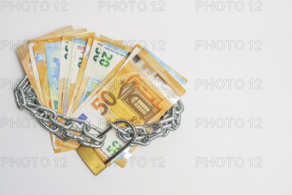 Pile of euro banknotes tied with a chain and a padlock isolated on a white background