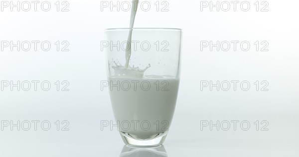 Milk being poured into Glass against White Background