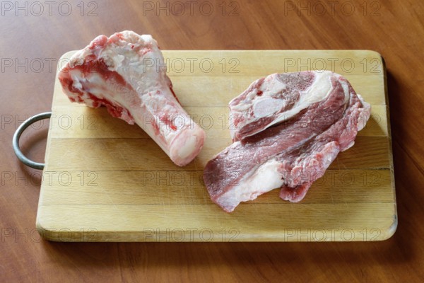 Meat of beef and marrowbone on a wooden cutting board, will be boil for the preparation of broth
