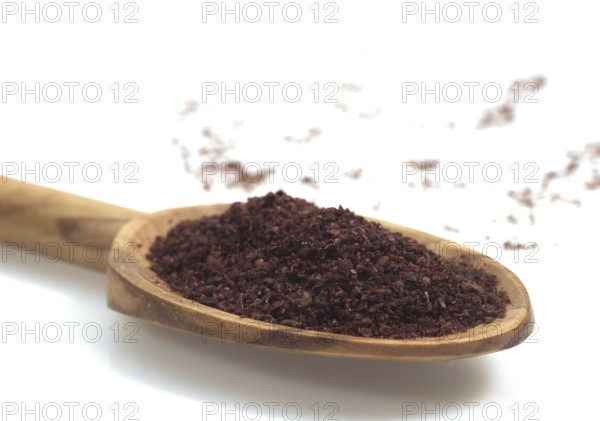 Sumac powder, spice in a spoon against white background