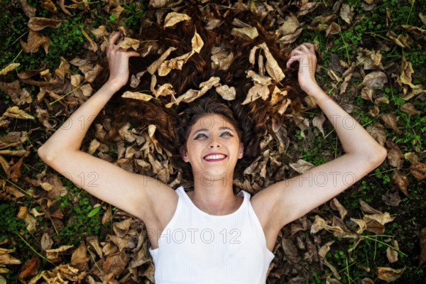 A happy young woman lies in the autumn leaves. Beautiful eyes, warm emotions