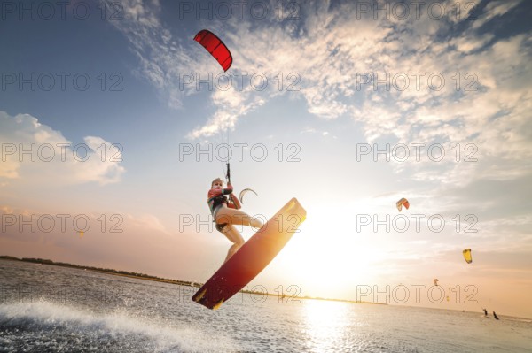 Sports shot of a young caucasian woman in a wetsuit doing a trick in the air against the backdrop