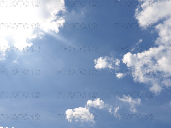 Bright hot sun on a blue summer sky with small clouds