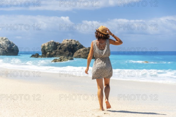 A woman walking on the turquoise water Megali Petra beach of Lefkada island, Ionian Sea, Greece,