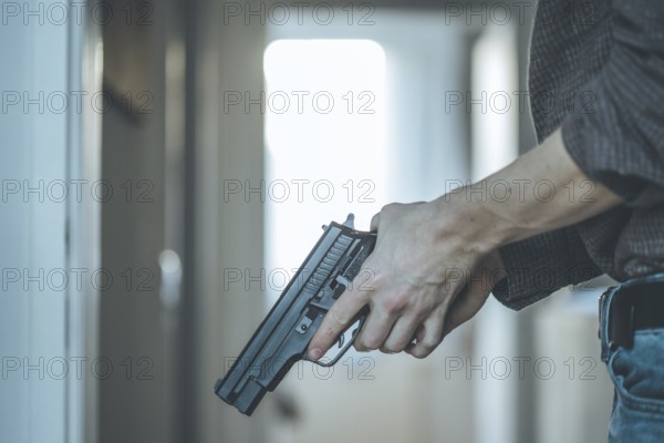 Undercover police agent is holding a black weapon in his hand, ready for shoot