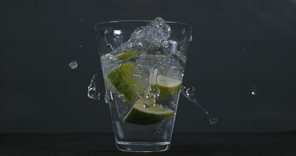Green Citrus (citrus aurantifolia), falling into a Glass of Water