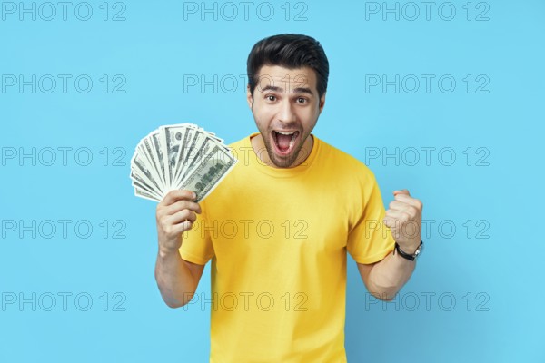 Happy excited man showing money banknotes on blue background. Business, win, income, success