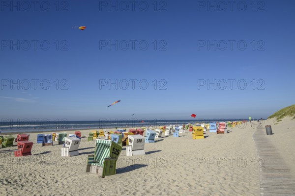 Colourful beach chairs and kites on a sunny beach with blue sky and sea, langeoog, east frisia,