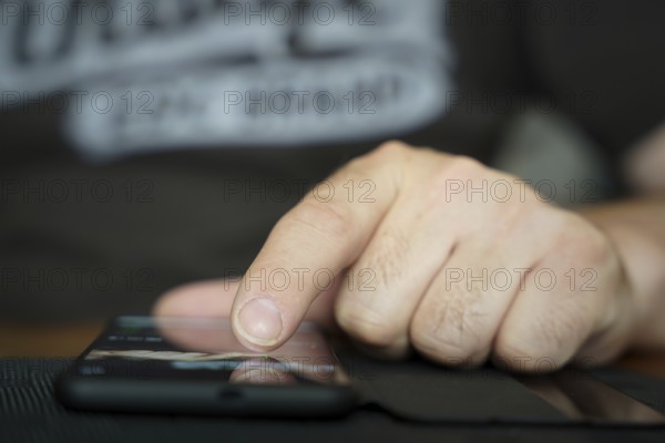 A person's fingers operate a smartphone lying on the table and w