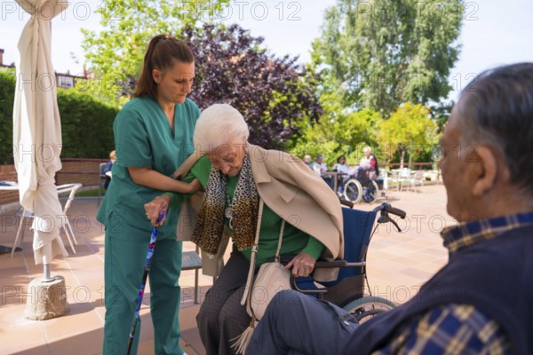 An elderly woman with the nurse in the wheelchair in the garden of a nursing home or retirement