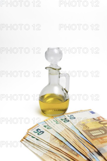 Euro banknotes in front of a bottle of olive oil isolated on a white background, oil price rise
