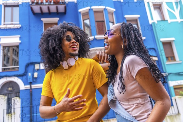 Close-up low angle view portrait of a cool african couple laughing talking in a colorful street