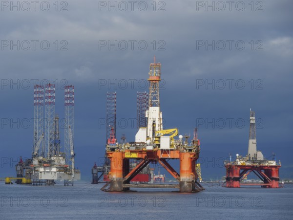 Several oil rigs are on the water under a dramatic cloudy sky, inverness, scotland, uk
