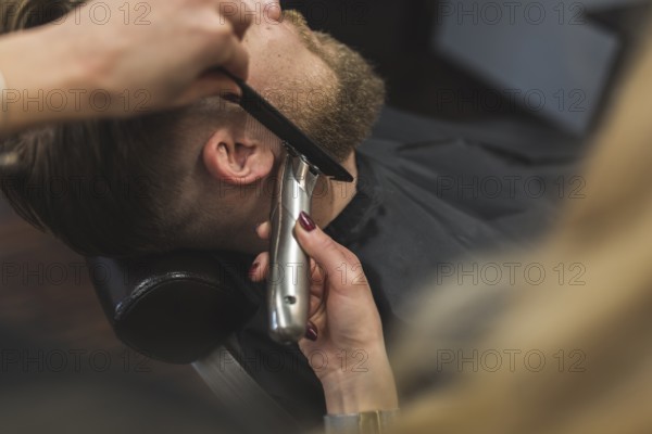 Anonymous woman trimming beard man