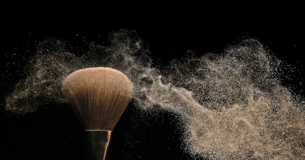 Make-up Brush spreading blush powder on black background