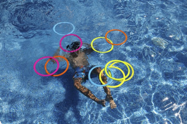 Boy playing with colourful rings in swimming pool, Province of Quebec, Canada, North America