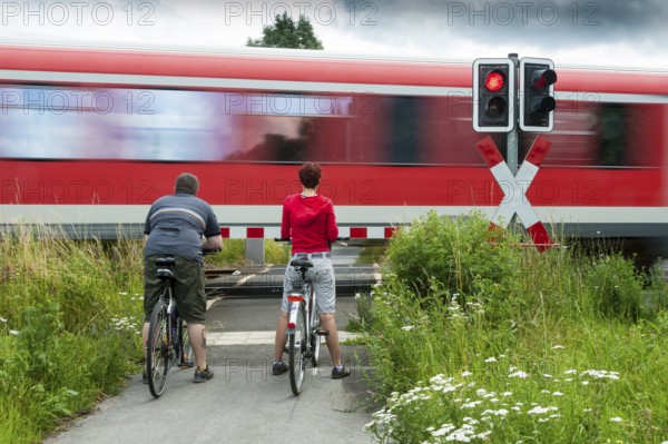Man and woman standing with bicycles at a closed railway crossing
