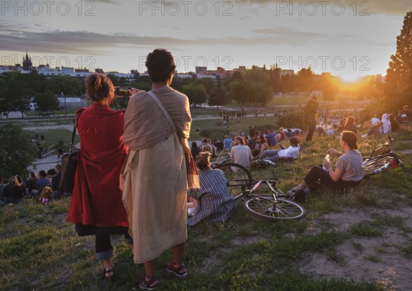 Germany, Berlin, 21. 206. 2020, Mauerpark, two woman, mobile phone photo, visitors on the meadow,