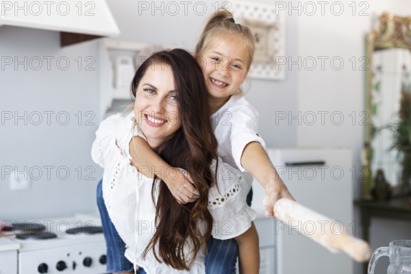 Happy mother daughter posing with kitchen roller