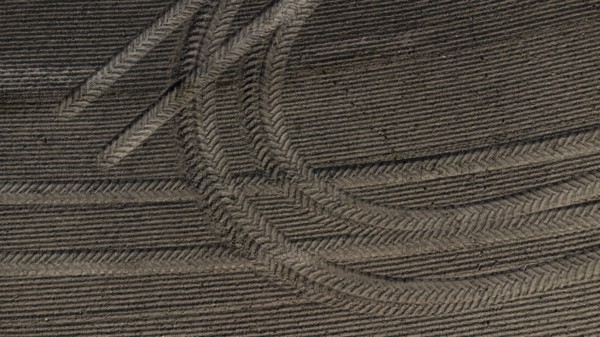 Tractor tyre tracks form an interesting pattern on a freshly cultivated field without vegetation,