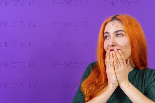 Redhead woman in studio photography making the gesture please on a purple background
