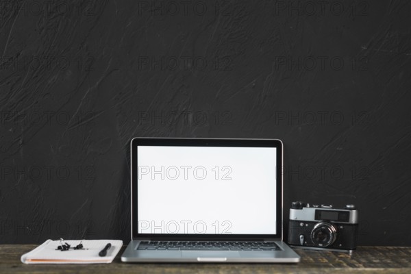 Retro old camera blank screen laptop with stationeries wooden table
