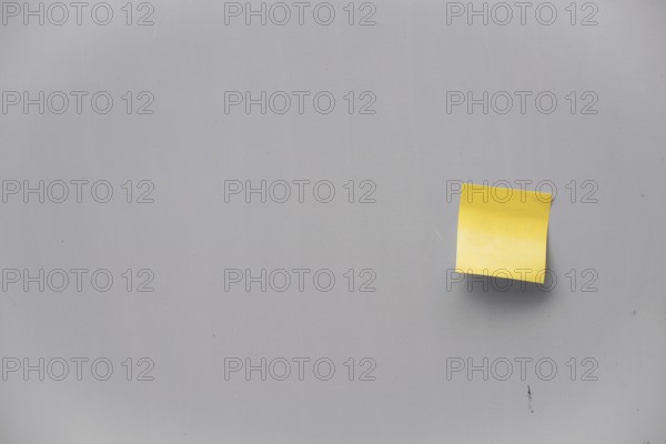Yellow post-it note on a grey wall