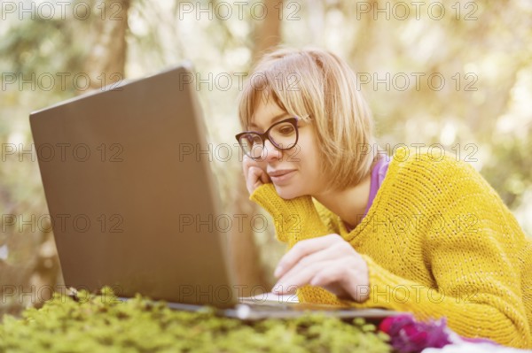 Toned image of a freelancer girl portrait in a yellow sweater and glasses looking thoughtfully at