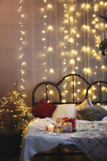 Tray with decorations and gift box placed on comfortable bed in cozy bedroom decorated for