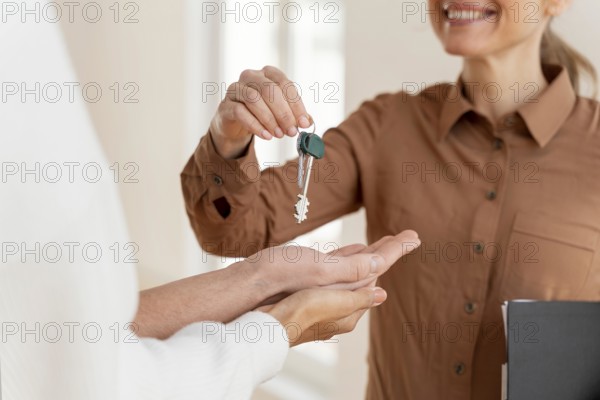 Smiley female realtor handing couple keys their new home