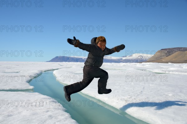 Inuit boy jumps over crevice in ice floe, Ellesmer, Eskimo, Inuit boy, Eskimo boy, releasable,