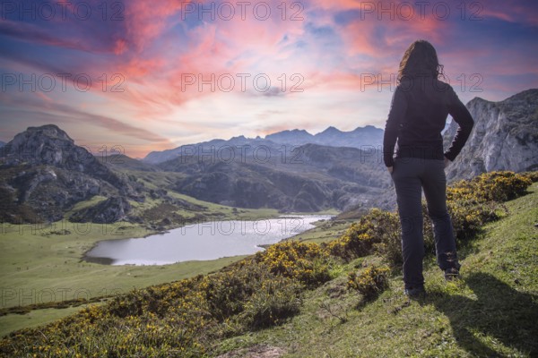 A young woman looking at the beautiful Covadonga lake in Asturias in a beautiful spring sunset,